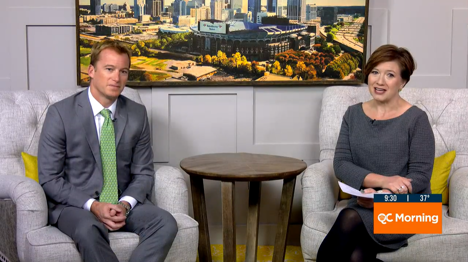 Two news anchors sit in armchairs on the QC Morning show set at 9:30 AM, 37°F, with a city skyline backdrop.